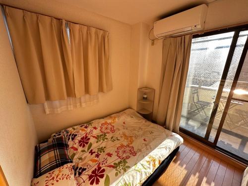 a small bedroom with a bed and a window at kaneshiro guest house in Tokyo