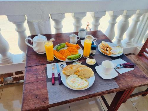 a table with plates of breakfast foods and orange juice at Chambres d'hôtes Beluga in Nosy Be