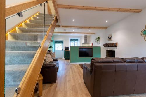 a living room with a staircase and a couch at Rural 5* Rookby Cottage, with large Hot Tub in Winton