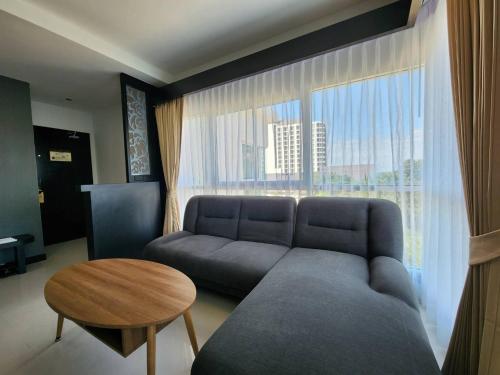 a living room with a couch and a large window at LHC HOTEL AND RESORT in Pattaya Central