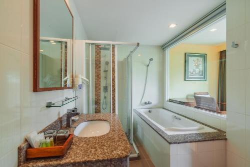 a bathroom with a sink and a shower and a tub at Elite Suites Patong in Patong Beach