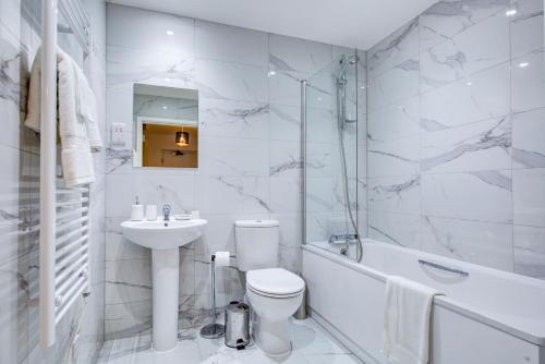 Hybrid Resi - Mitcham close to Tooting and Wimbledon في ميتشام: حمام أبيض مع حوض ومرحاض وحوض استحمام