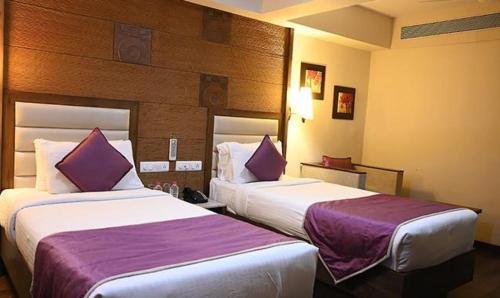 two beds in a hotel room with purple sheets at FabHotel Prime Ace Grand in Vadodara