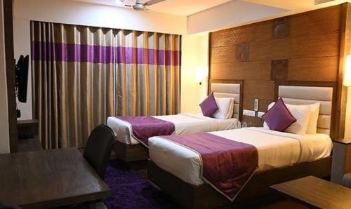 a hotel room with two beds and a table at FabHotel Prime Ace Grand in Vadodara