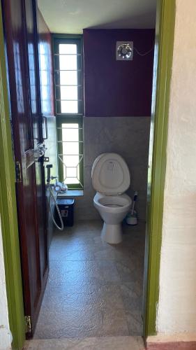 a bathroom with a white toilet in a room at Thendral: Delightful homestay on a hill near Ooty in Naduvattam