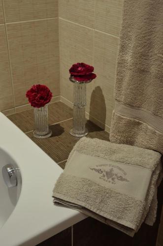 - une salle de bains avec 2 fleurs rouges sur un lavabo dans l'établissement Guest House Château le But proche de Périgueux en Dordogne, à Léguillac-de-Lauche