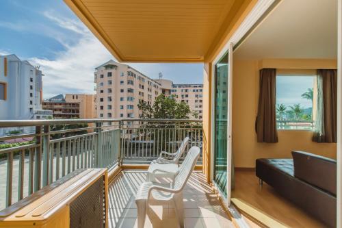 a balcony with two white chairs and a couch at Elite Suites Patong in Patong Beach