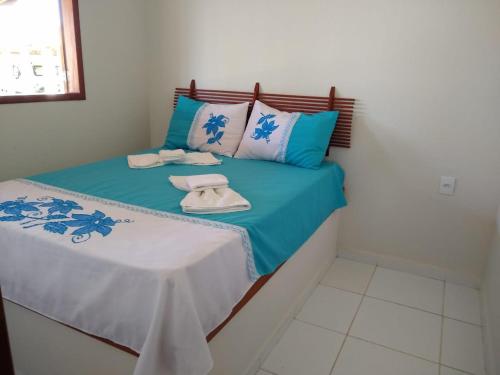 Una cama con sábanas azules y blancas y toallas. en Condomínio e Pousada Chalés Sossego do Gostoso, en São José
