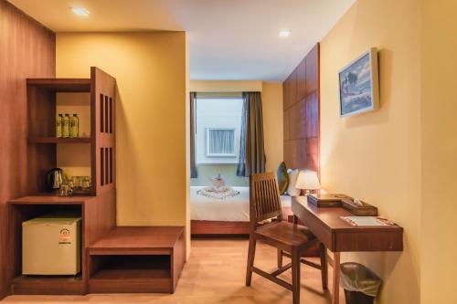 a hotel room with a desk and a bed at Elite Suites Patong in Patong Beach