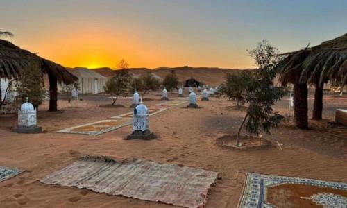 a group of figurines in the desert with the sunset at Your journey starts here in Merzouga