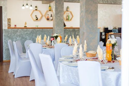 un comedor con mesas blancas y sillas blancas en Pensiunea Teo, en Bilbor