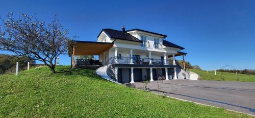 een groot wit huis met een veranda op een heuvel bij Villa Hojnik in Videm pri Ptuju