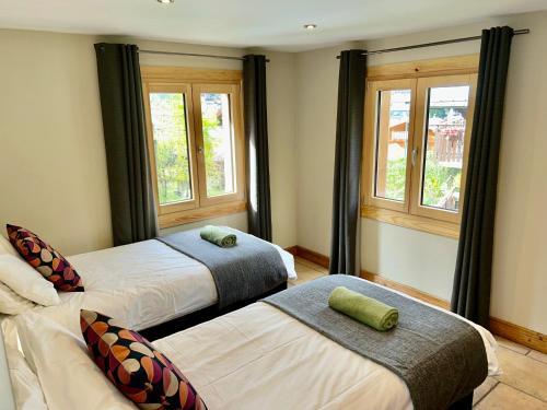 deux lits dans une chambre avec deux fenêtres dans l'établissement 3 Bedrooms, Whole floor, New Kitchen, Town Centre, à Chamonix-Mont-Blanc