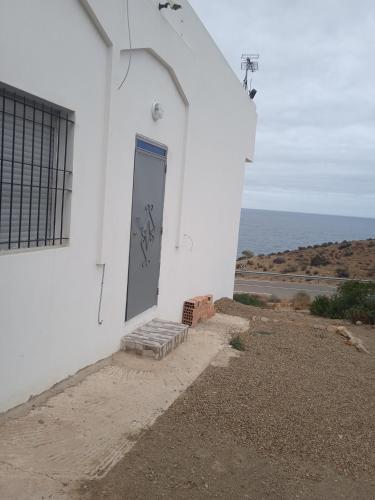 un edificio bianco con una porta blu accanto all'oceano di Plage calairis 