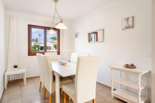a white dining room with a white table and chairs at Villa JOJO & CLEO in Port d'Addaia