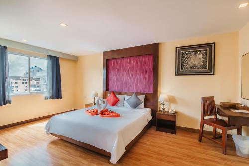 a hotel room with a large bed and a desk at Elite Suites Patong in Patong Beach