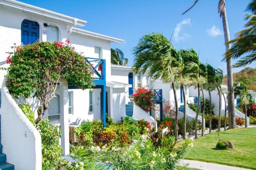 a row of white houses with flowers and palm trees at Trade Winds Hotel in Dickenson Bay