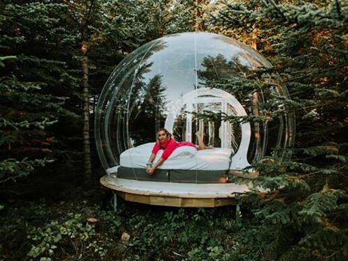 a woman laying on a bed in a glass dome at Buubble Hotel - Ölvisholt in Selfoss