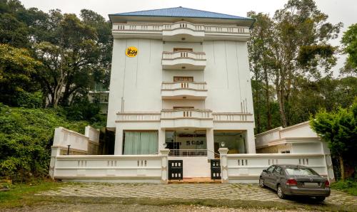 a large white building with a car parked in front of it at Itsy By Treebo -Classiyo Munnar Crown Resorts in Munnar