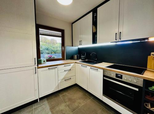 uma cozinha com armários brancos e um aparelho preto em Ferienhaus Ella em Trautskirchen