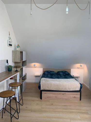 a bedroom with a bed and a desk and two stools at La Pose Normande in La Cerlangue