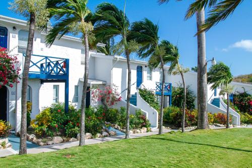 a white house with palm trees in front of it at Trade Winds Hotel in Dickenson Bay