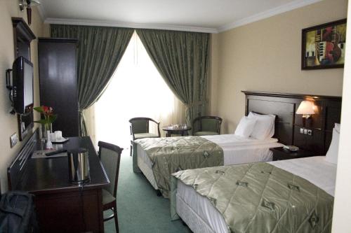 a hotel room with two beds and a desk at Hotel Rapsodia City Center in Botoşani