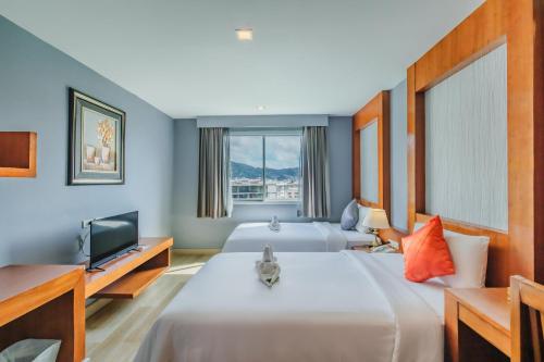 a hotel room with two beds and a television at Elite Suites Patong in Patong Beach