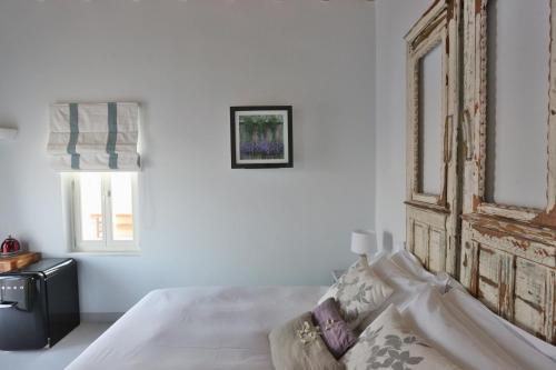 a white bedroom with a bed and a window at 1901 Hermoupolis in Ermoupoli