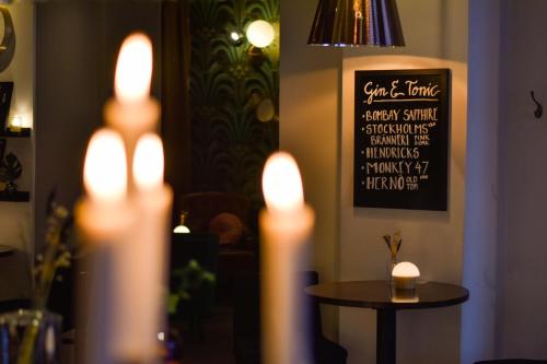 a table with lit candles in a room with a chalkboard at Home Hotel Drott in Karlstad