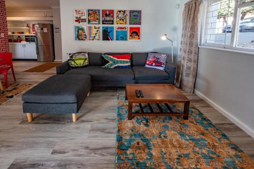 a living room with a couch and a coffee table at Die Brandhuis Sleeps 4, One minute walk to the Beach! in Gordonʼs Bay