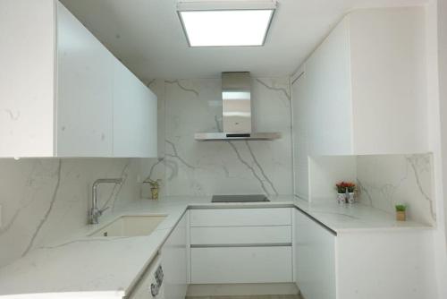 a white kitchen with white cabinets and a skylight at Gran casa ideal para familias in Atarfe