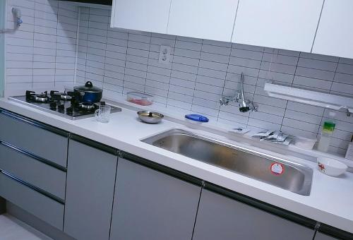 um balcão de cozinha com um lavatório e um fogão em Subhanallah guest house em Yangsan