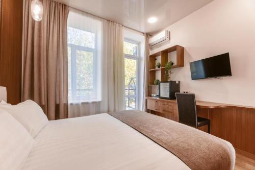 a bedroom with a bed and a tv and a window at Park Hotel Tskaltubo - Balneo Resort in Tsqaltubo