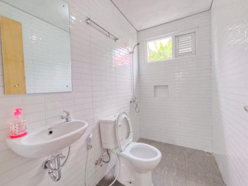 a white bathroom with a toilet and a sink at Villa Cisarua Wulan in Brujul