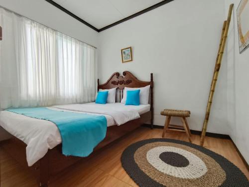 a bedroom with a bed with blue pillows and a rug at Villa Cisarua Wulan in Brujul