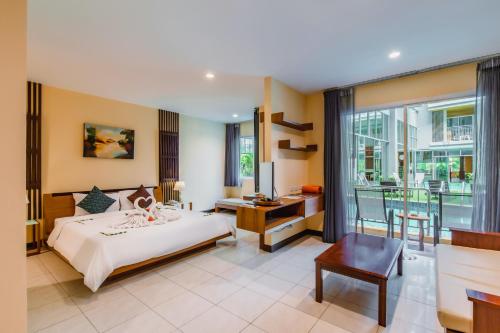 a bedroom with a bed and a desk and a window at Elite Suites Patong in Patong Beach