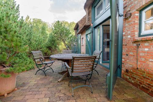 a patio with a table and chairs on a brick building at Fleederbeerstuv in Wrixum