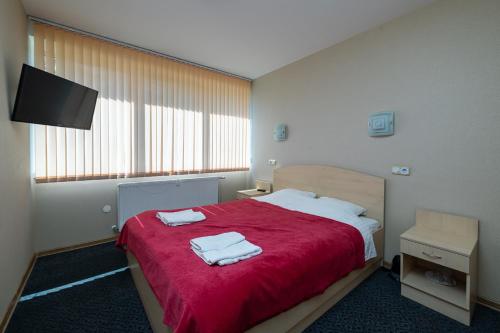 a bedroom with a red bed with two towels on it at Balvi Hotel in Balvi