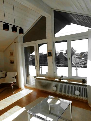 - un salon avec une table en verre et de grandes fenêtres dans l'établissement Charmante Wohnung, à Aalen