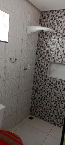 a bathroom with a shower with a tiled wall at Casa de praia giovani in Aracaju