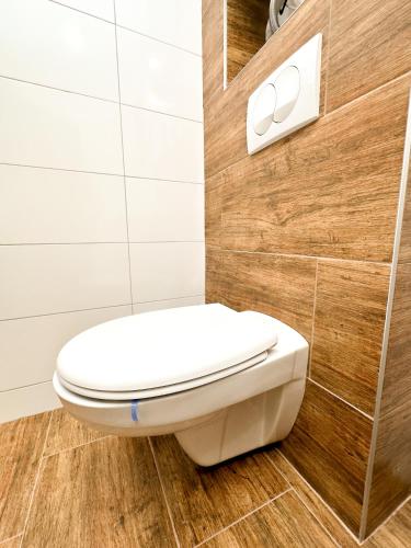 a white toilet in a bathroom with a wooden wall at Kiko apartmani LUX in Zrenjanin
