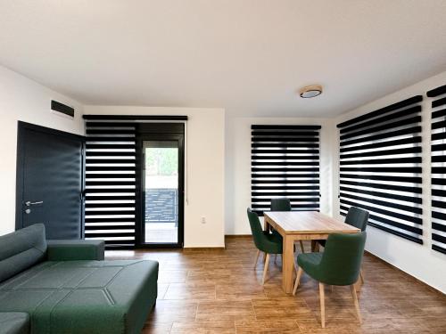 a living room with a wooden table and green chairs at Kiko apartmani LUX in Zrenjanin