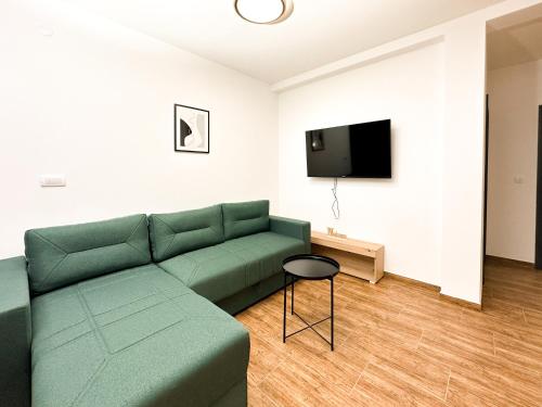 een woonkamer met een groene bank en een tv bij Kiko apartmani LUX in Zrenjanin