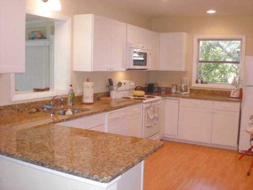 een keuken met witte kasten en marmeren aanrechtbladen bij Palm Cottage #54605 in Holmes Beach