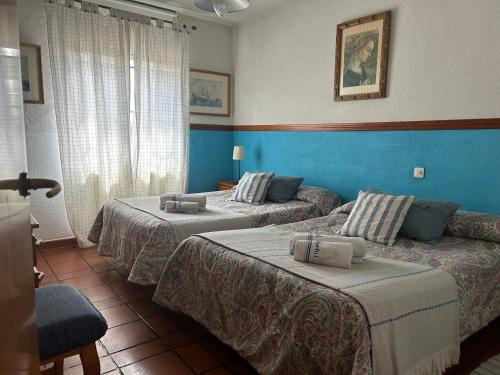 two beds in a hotel room with blue walls at Casa rural EL CASTILLO DE CIRUELAS in Ciruelas