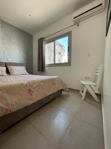 a bedroom with a bed and a window and a chair at Rent a Home Hurghada in Hurghada