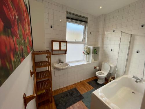 een badkamer met een bad, een toilet en een wastafel bij Spacious Family Flat in Londen