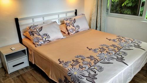 ein Bett in einem Schlafzimmer mit einer Bettdecke mit Blumen darauf in der Unterkunft Dovass Self Catering Apartments in Takamaka