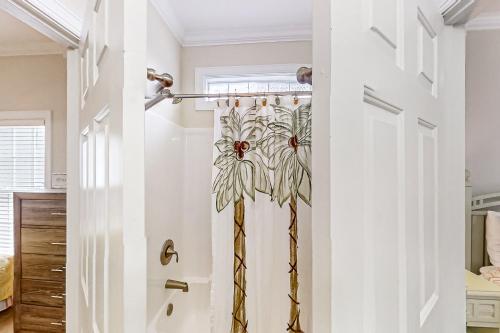 a bathroom with a door with a flower shower curtain at A Shore Pleasure in Myrtle Beach